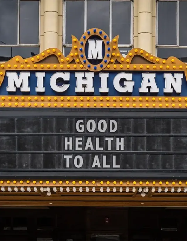 Michigan Theater marquee sign lit with bulbs reading “GOOD HEALTH TO ALL.”