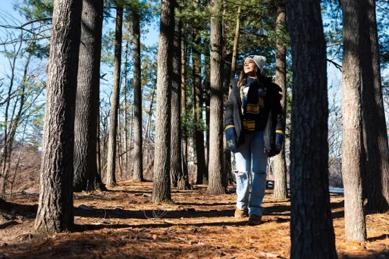 U-M student walking through a wooded area.