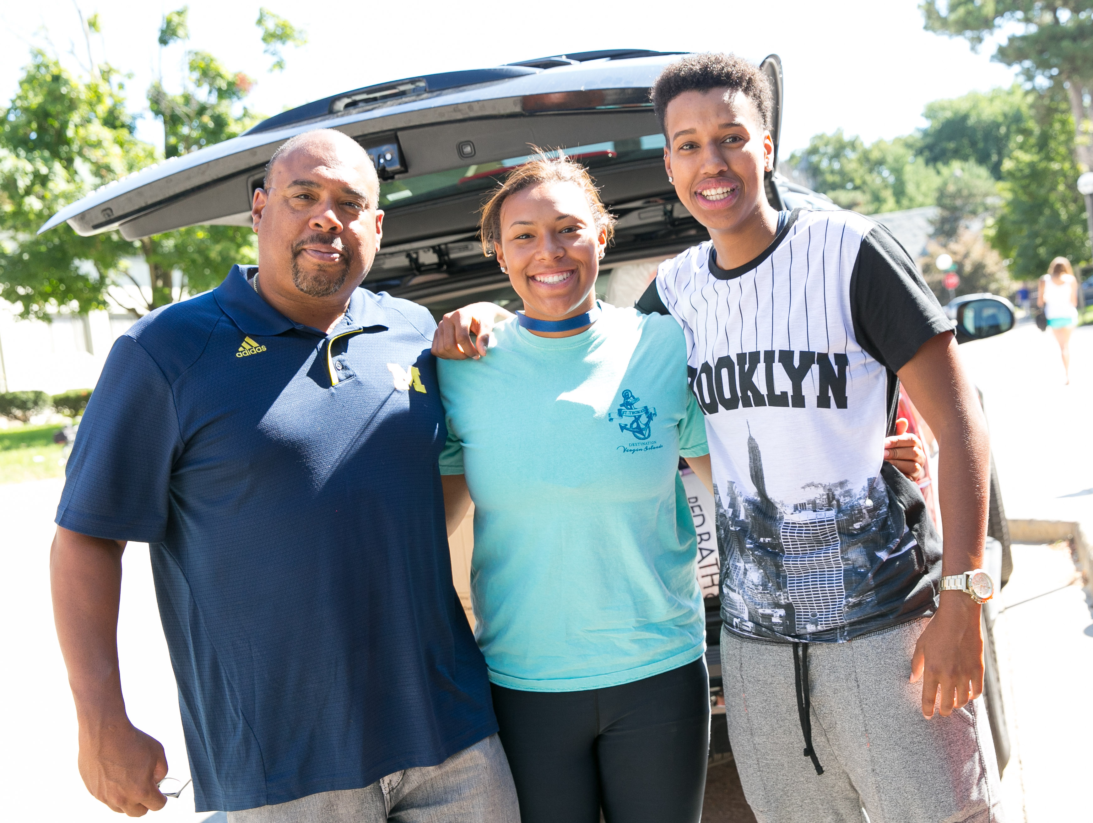 Family posing near car on move-in day.
