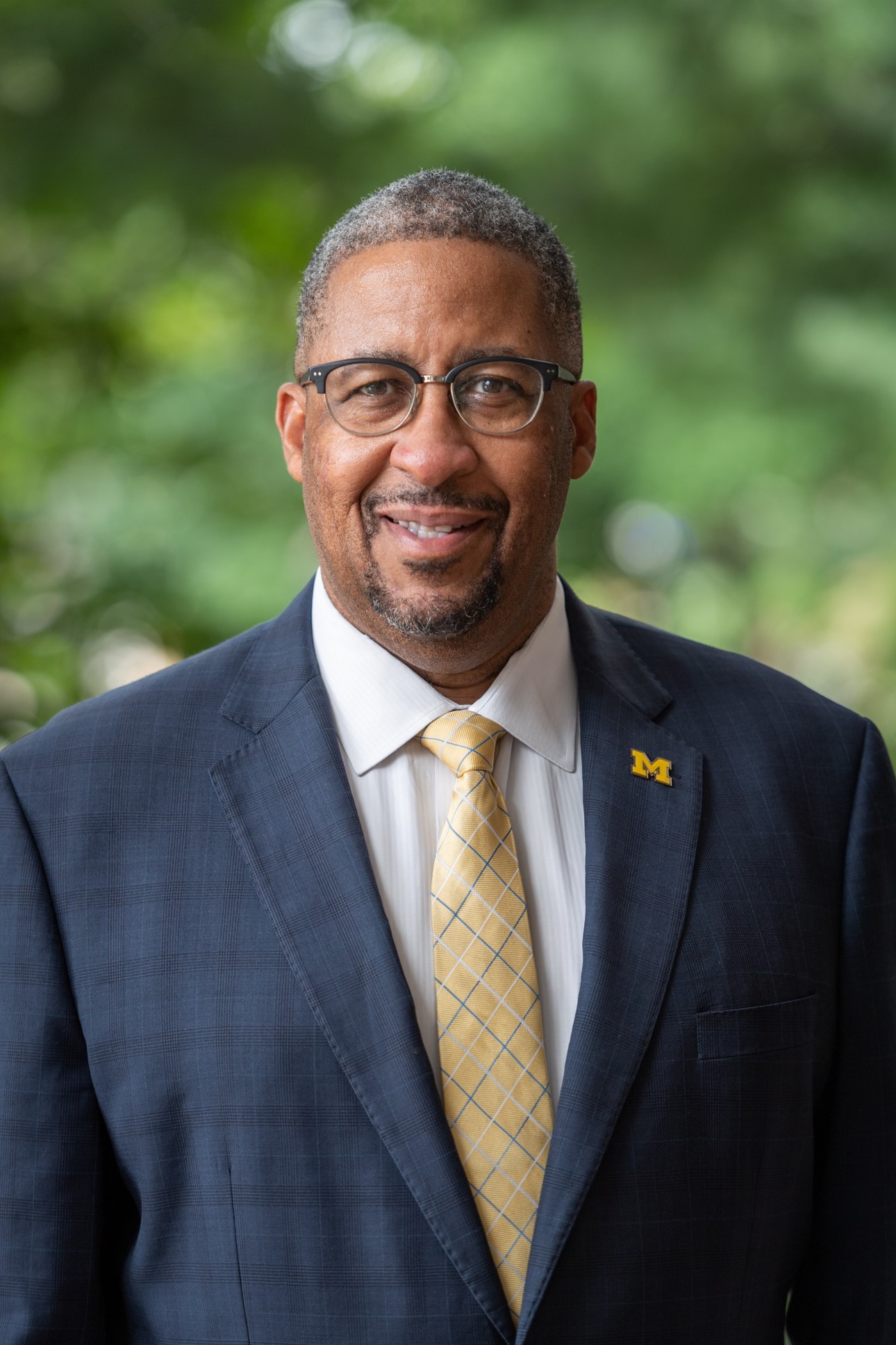 Professional Photo of Vice President for Student Life, Martino Harmon, wearing a navy blazer and maize tie