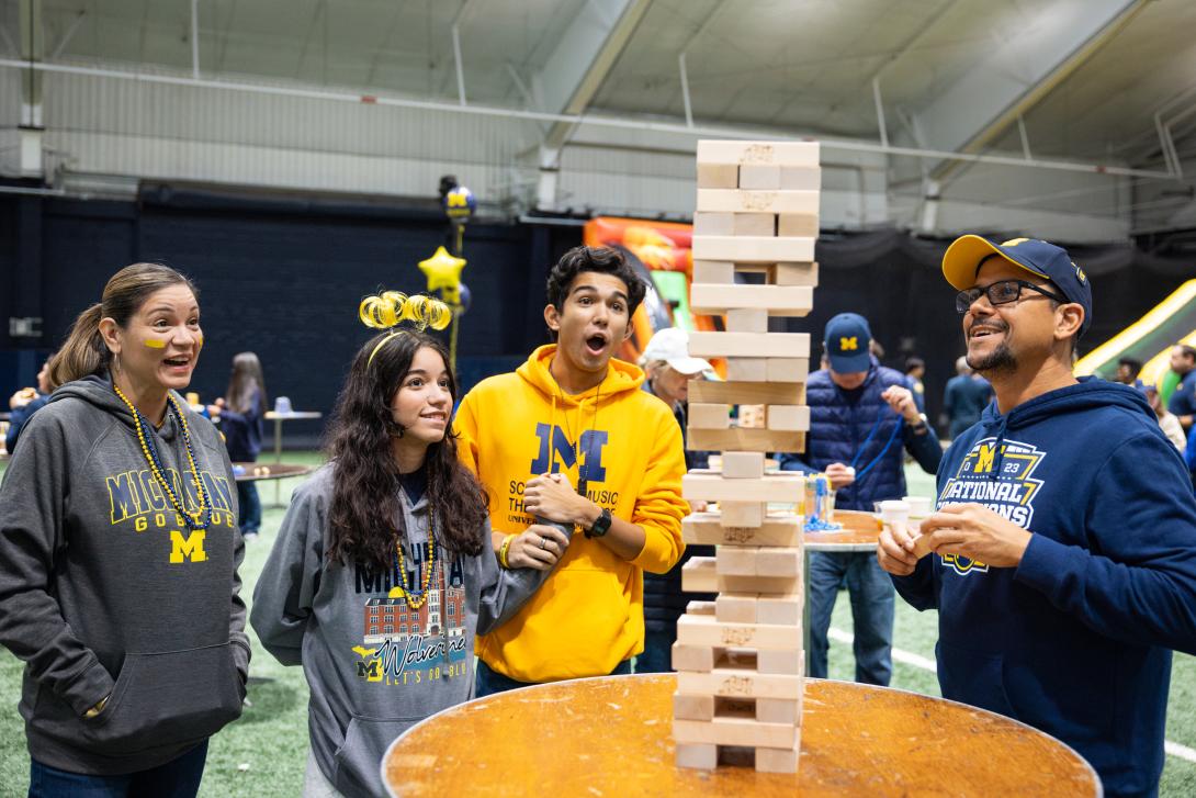 Family of four playing tabletop Jenga at the MFamily Tailgate in Oosterbaan Fieldhouse