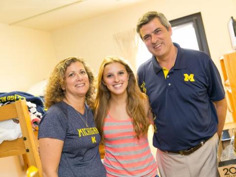A new student stands with her parents in her residence hall room during Move-In