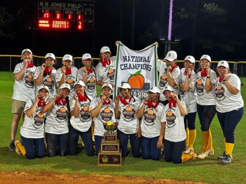 The Club Softball team holding a National Championship banner.