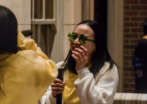 A student wearing clover glasses laughing while at a U-M St.Patrick's Day event.
