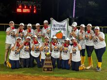 The Club Softball team holding a National Championship banner.
