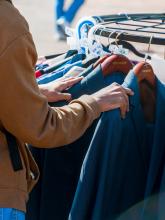 Close up of a person looking through a clothing rack filled with professional attire.